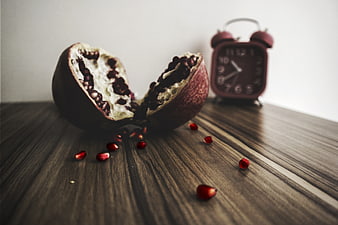 Split pomegranate with scattered seeds on wooden table