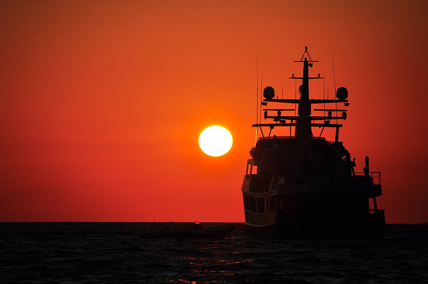 Silhouette of Fishing Boat Against Vibrant Orange Sunset