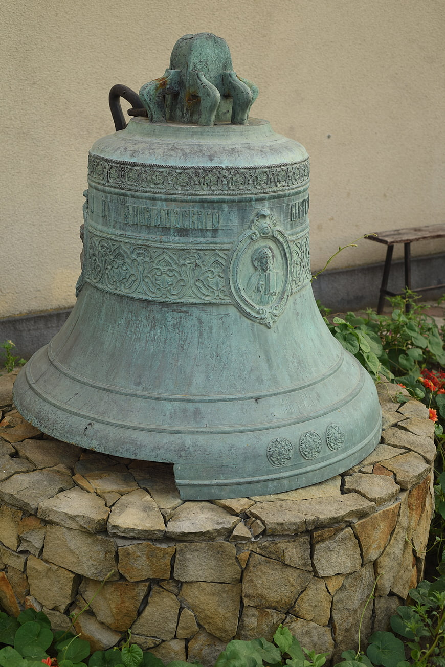 Antique Bronze Bell on Stone Pedestal in Garden