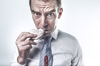 Messy businessman eating donut with intense expression