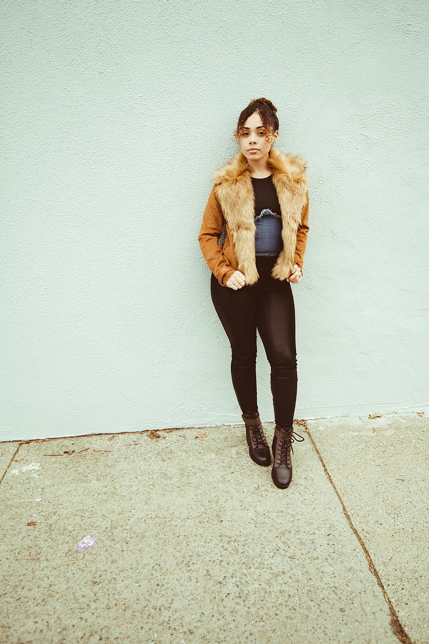 Stylish Woman in Fur Jacket Against Mint Wall