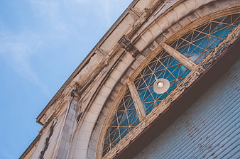 Low angle view of vintage arched window and blue sky