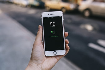 Hand holding smartphone with app interface on street background