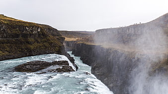 Majestic waterfall cascading into a misty canyon gorge
