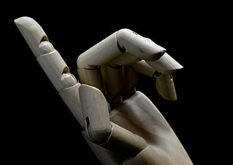Close-up of wooden artist mannequin hand on black background