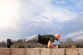 Athletic Man Doing Plank Exercise on Outdoor Stone Wall