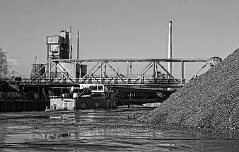 Black and white industrial landscape with bridge and coal pile