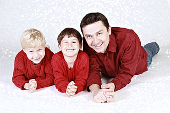 Happy Father and Two Sons in Red Sweaters Lying Down