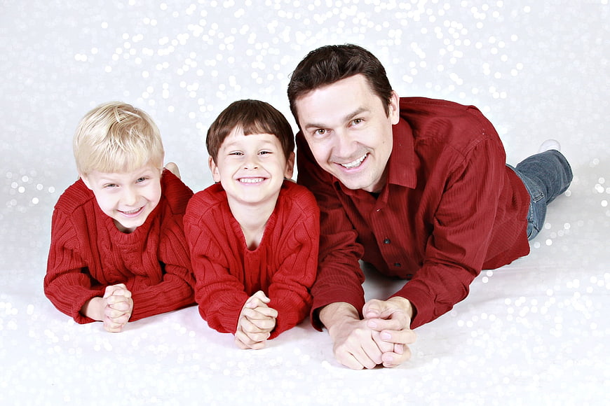 Happy Father and Two Sons in Red Sweaters Lying Down