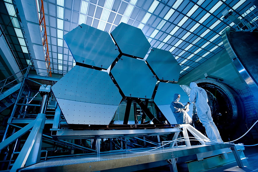 Astronauts assembling hexagonal telescope mirrors in a cleanroom