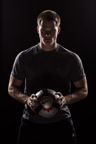 Portrait of male soccer player holding ball in studio