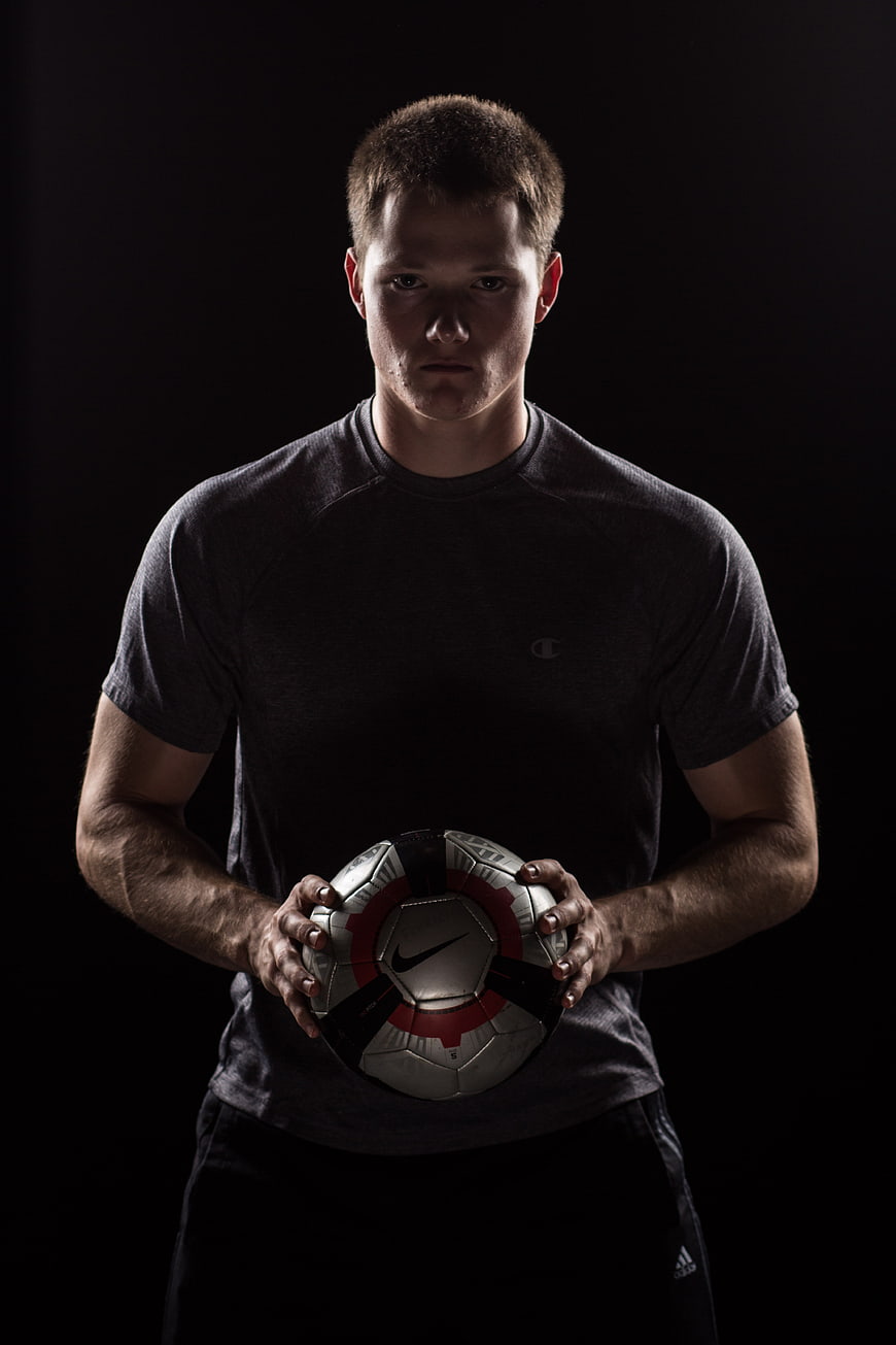 Portrait of male soccer player holding ball in studio