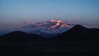 Snow-Capped Mountain Peak at Twilight with Silhouetted Hills
