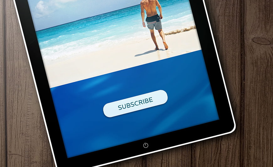 Tablet displaying subscribe button on beach background