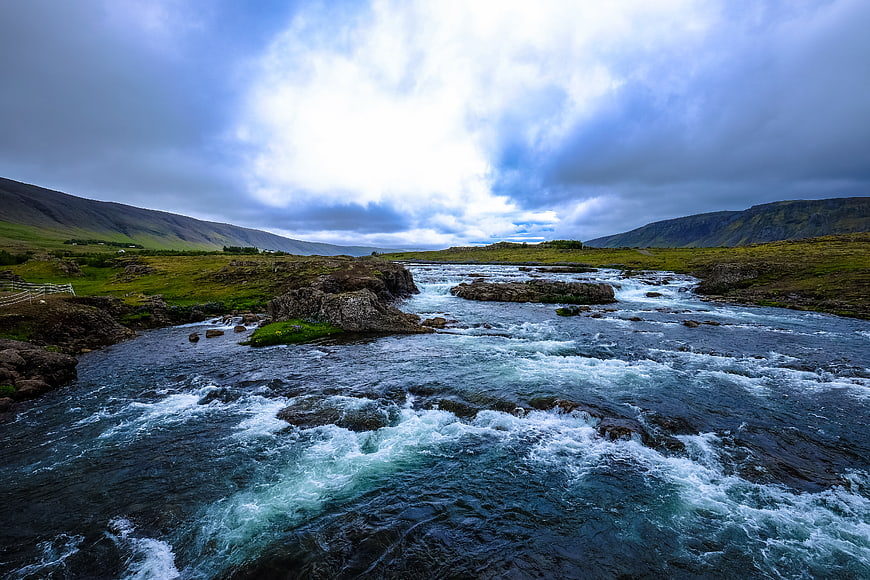 Dramatic River Landscape with Rushing Water and Cloudy Sky