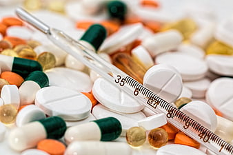 Glass Thermometer on Pile of Colorful Medical Pills