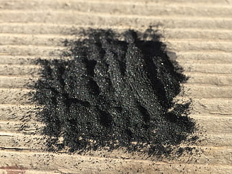 Close-up of black charcoal powder on weathered wooden surface