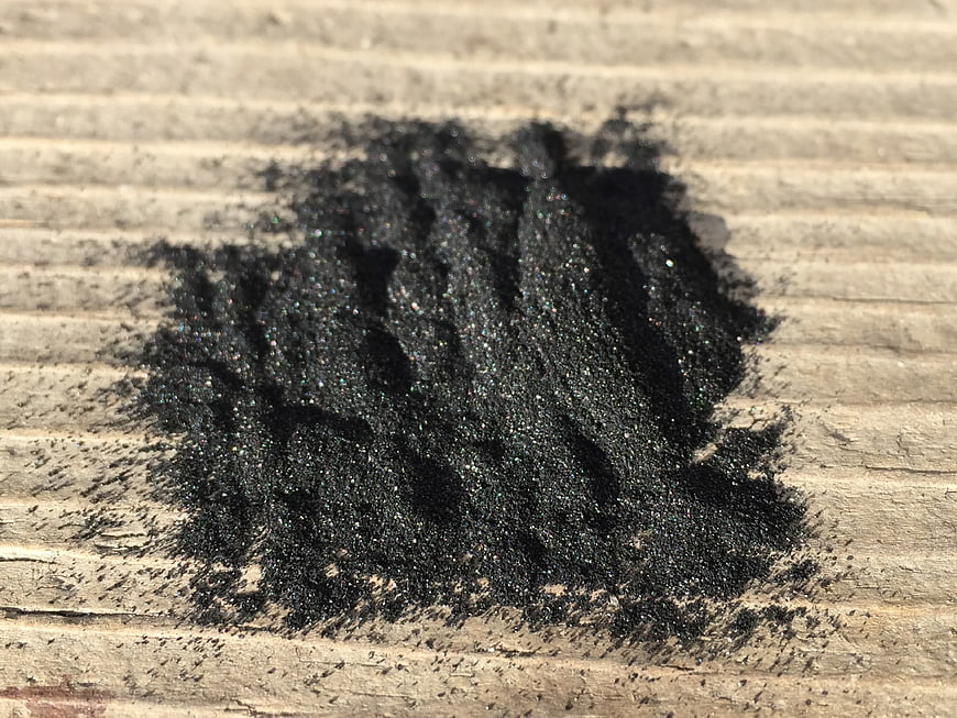 Close-up of black charcoal powder on weathered wooden surface