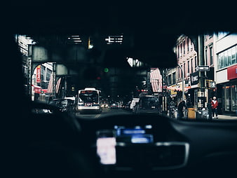 View from car dashboard driving under elevated train tracks in city