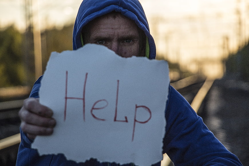 Man holding help sign on railway tracks