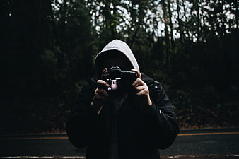 Anonymous Photographer in Hoodie Taking Photo in Dark Forest