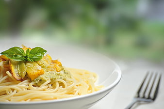 Pasta with pesto sauce and roasted vegetables on white plate