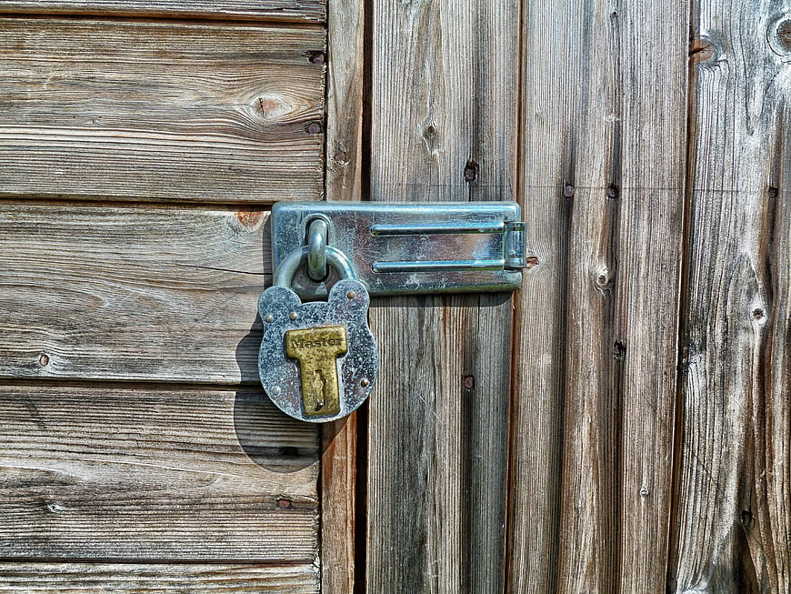 Weathered Metal Padlock Securing Aged Wooden Garden Shed Door