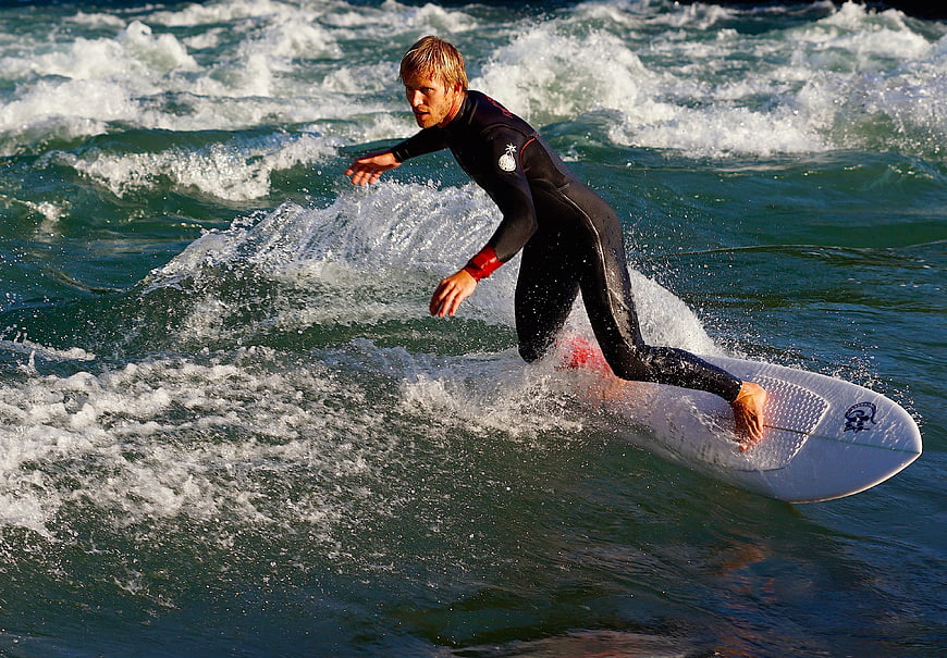 Male surfer riding a wave in a black wetsuit