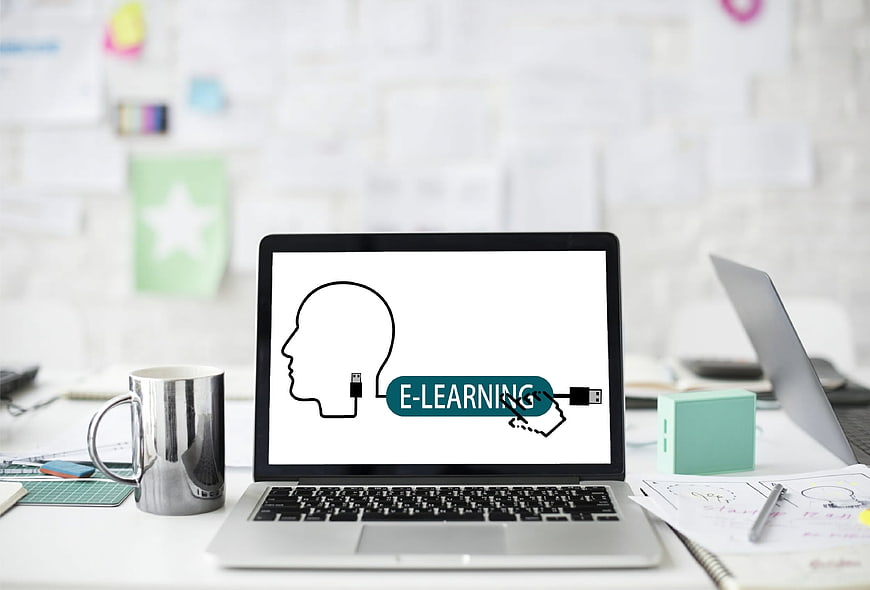 Laptop displaying e-learning concept with head and USB plug icon on desk