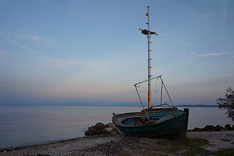 Old Rusty Fishing Boat on Pebble Beach at Dusk