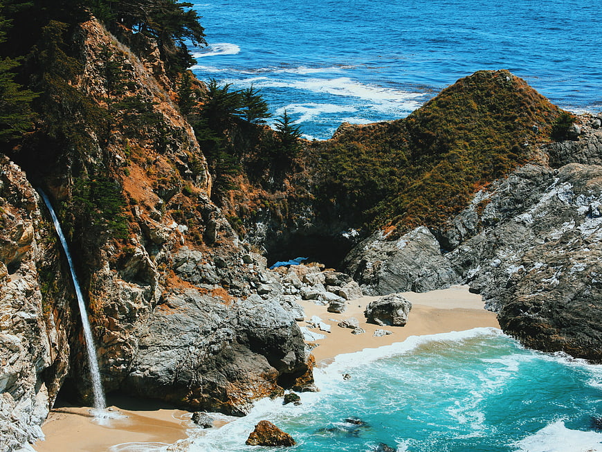 McWay Falls waterfall cascading into secluded sandy cove