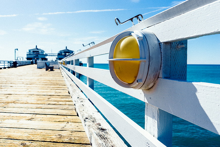 Yellow Pier Light on Wooden Dock by Blue Ocean