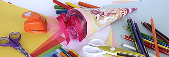 Colorful school supplies and party cone on desk