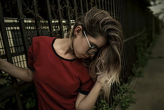 Woman in Red Shirt Leaning Against Metal Fence
