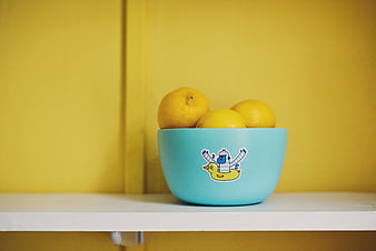 Blue Bowl with Lemons on Yellow Background