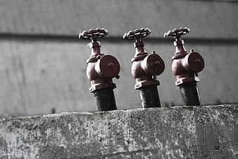 Three red industrial fire sprinkler valves on concrete wall