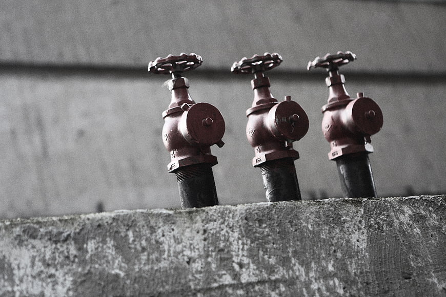 Three red industrial fire sprinkler valves on concrete wall