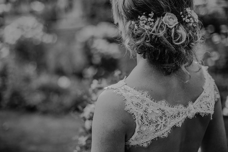 Black and white back view of bride with lace dress and flowers