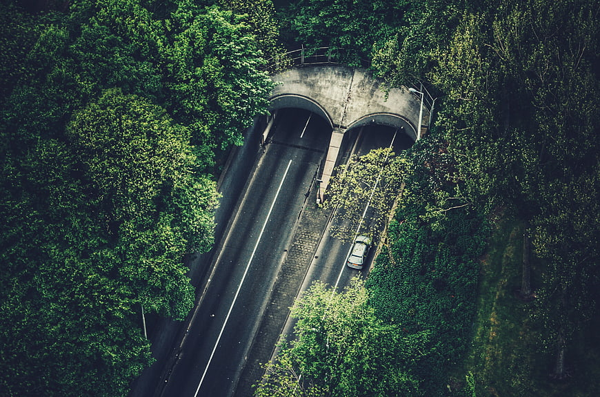 Aerial View of Car Driving Through Forest Tunnel