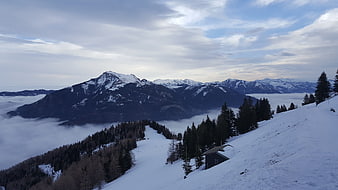 Snowy mountain ridge with sea of clouds and alpine hut