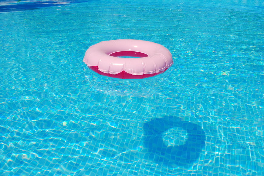 Pink inflatable ring floating in clear blue swimming pool water