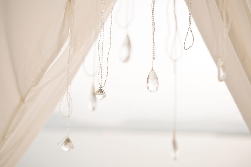Hanging crystal pendants and beads on white fabric background