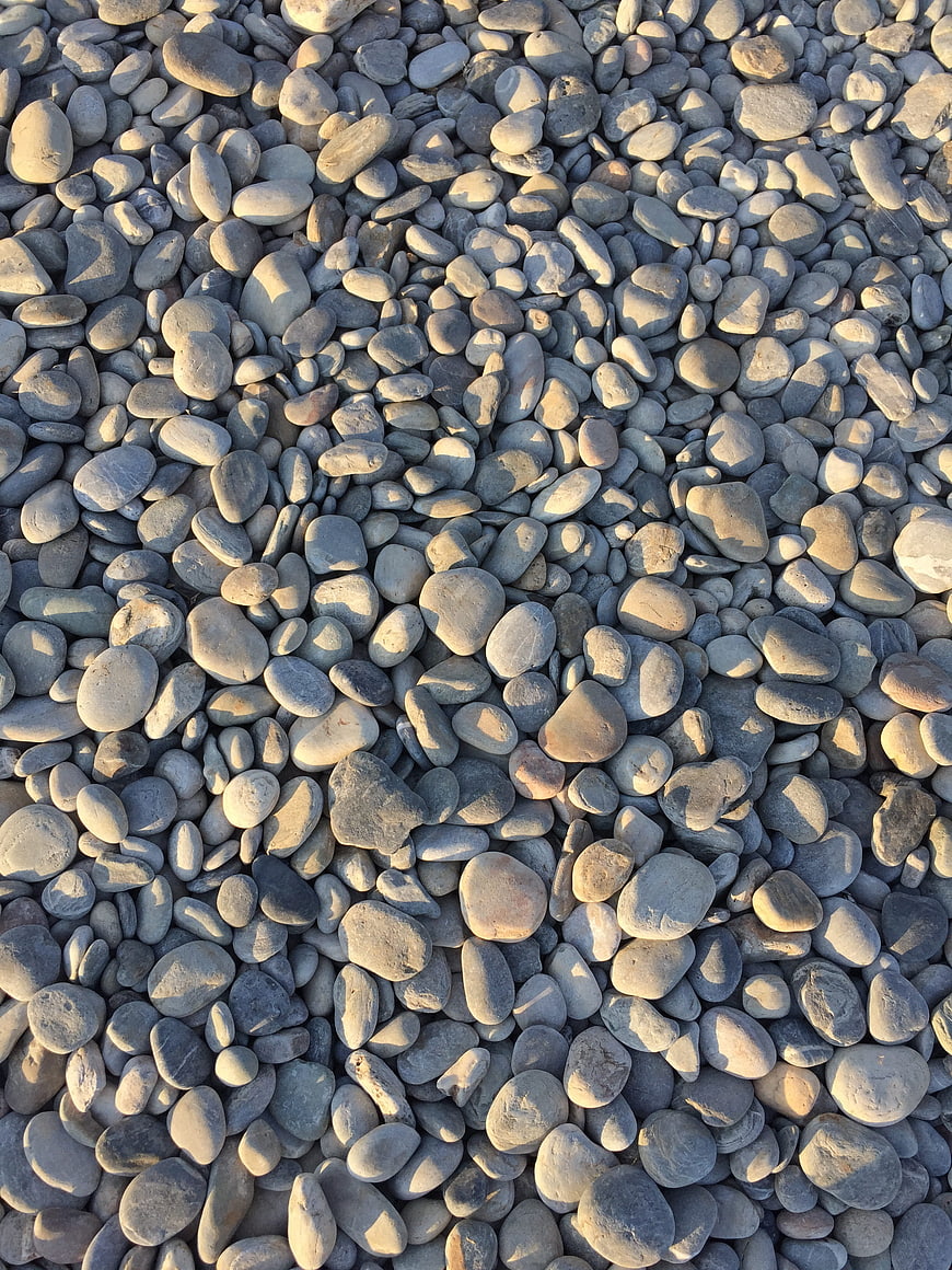 Smooth gray pebbles texture with golden hour sunlight