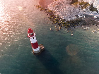 Aerial View of Red and White Lighthouse in Ocean at Sunset