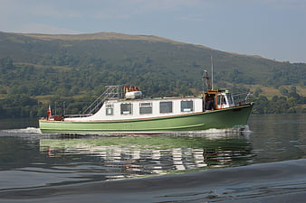 Green and white steamer boat cruising on a calm lake