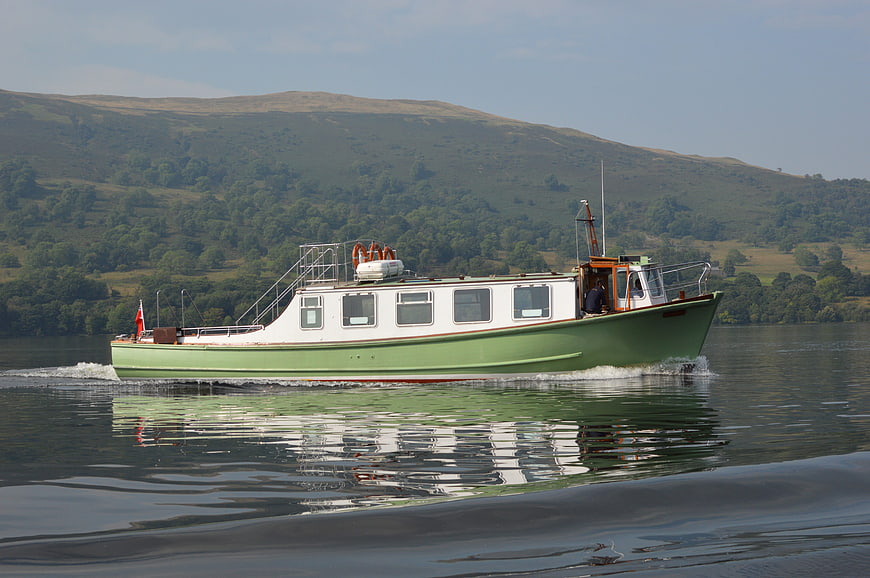 Green and white steamer boat cruising on a calm lake