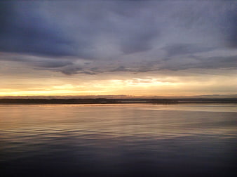 Serene Sunset Over Calm Water with Cloudy Sky