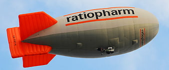 Orange and white advertising blimp flying in blue sky
