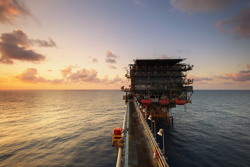 Offshore oil platform at sunset with dramatic sky