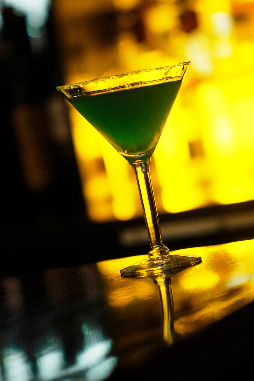 Green cocktail in martini glass on bar counter